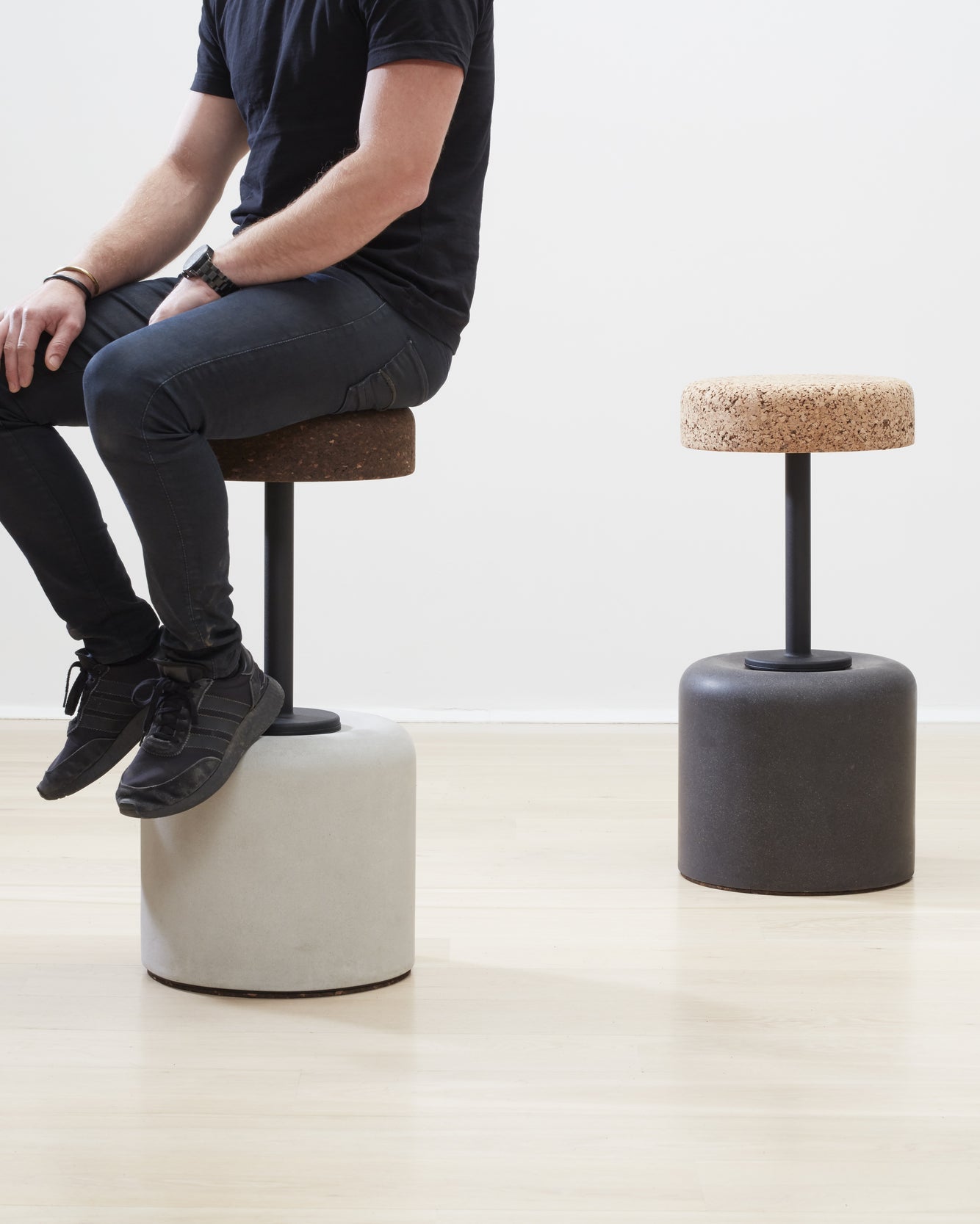 Designer Laurie Wiid van Heerden demonstrates the scale of Kanju's Wiid Swivel Cork and Concrete Barstool, offering a real-world perspective on its size and ergonomic design. This image captures Laurie seated on the innovative barstool, which combines the warmth of cork with the strength of concrete, showcasing the piece's functional elegance and sustainable approach to modern furniture design.
