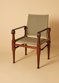 Stylish and comfortable chair with a warm mahogany frame and a canvas back and seat, positioned against a muted background that accentuates its clean lines and sophisticated design suitable for luxury interior decor.