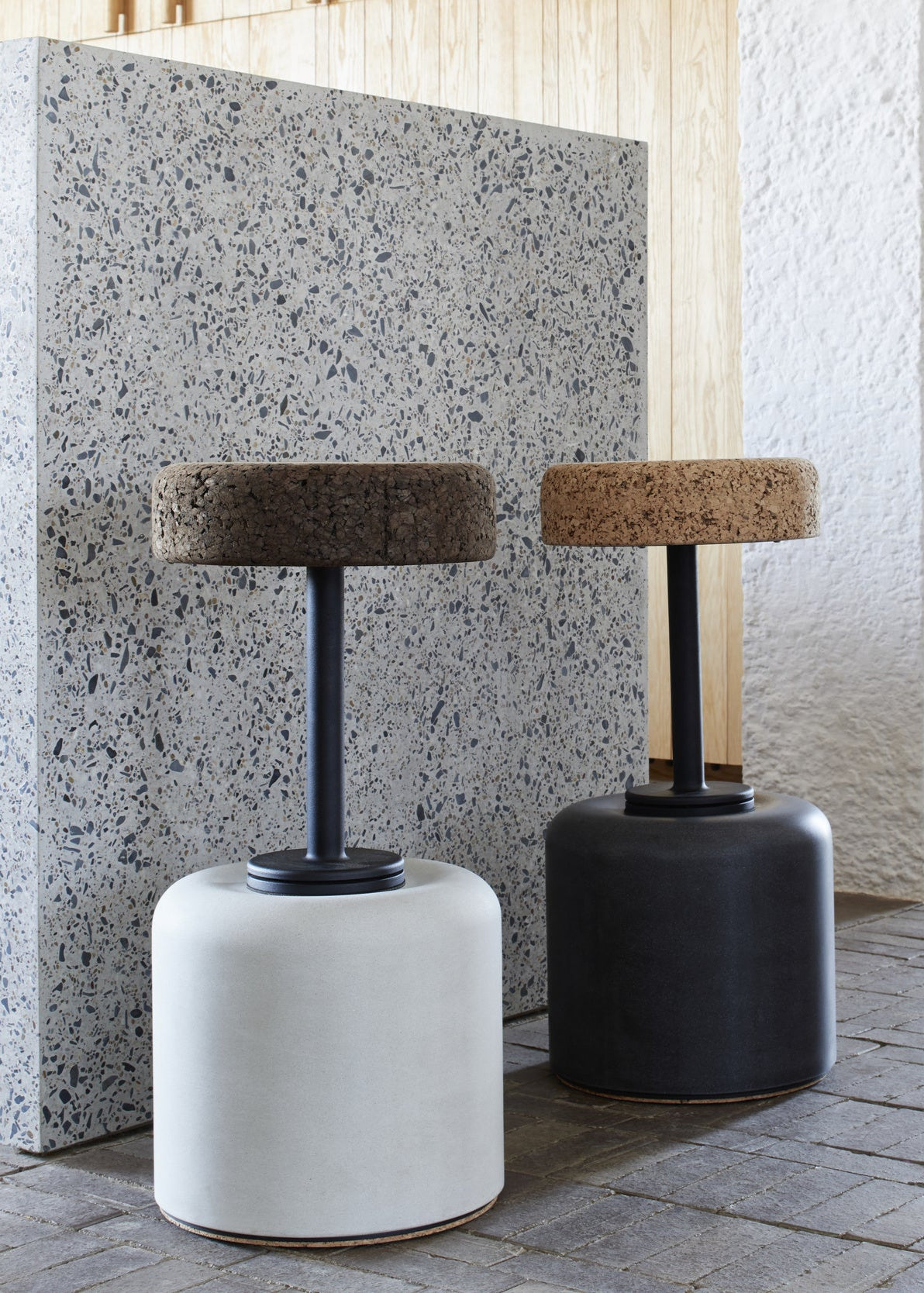 Stylish kitchen setting featuring Kanju's Wiid Swivel Cork and Concrete Barstools: one in Natural Grey Concrete with Dark Cork seat and another in Charcoal with Light Cork. This image illustrates the barstools' perfect fit in a modern kitchen, highlighting their sleek design, swivel functionality, and the elegant contrast of materials and colors. The barstools add a touch of contemporary sophistication and sustainable luxury next to the kitchen counter.