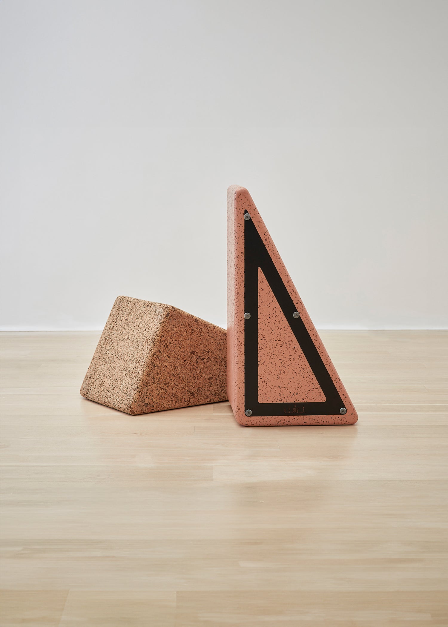 Close-up view of the bottom details of Kanju's Wiid Painted Triangle Cork Seat in a soft pink shade, highlighting the meticulous craftsmanship and unique design. The eco-friendly cork seat showcases innovative construction techniques, offering both style and sustainability in a contemporary home decor piece