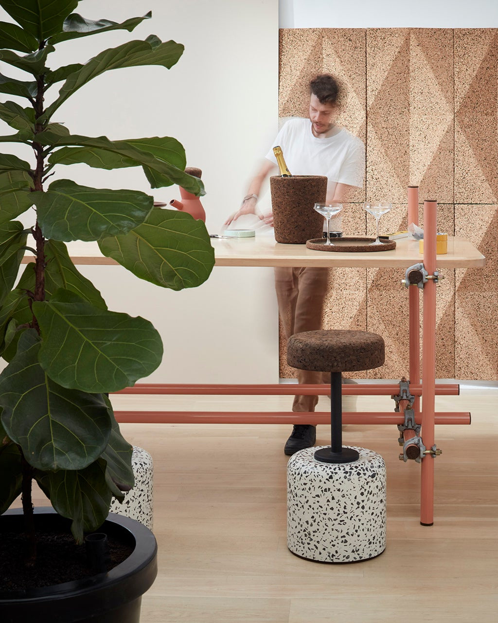 Contemporary work area elegantly styled with Kanju's Wiid Cork and Concrete Swivel Barstool in Terrazzo and Dark Cork, complemented by Wiid cork panels on the walls. This setup showcases a harmonious blend of textures and materials, highlighting the stool's unique design and the natural aesthetic of cork. The terrazzo base adds a splash of artistic detail, creating a functional yet inspiring workspace that emphasizes sustainability and modern style.