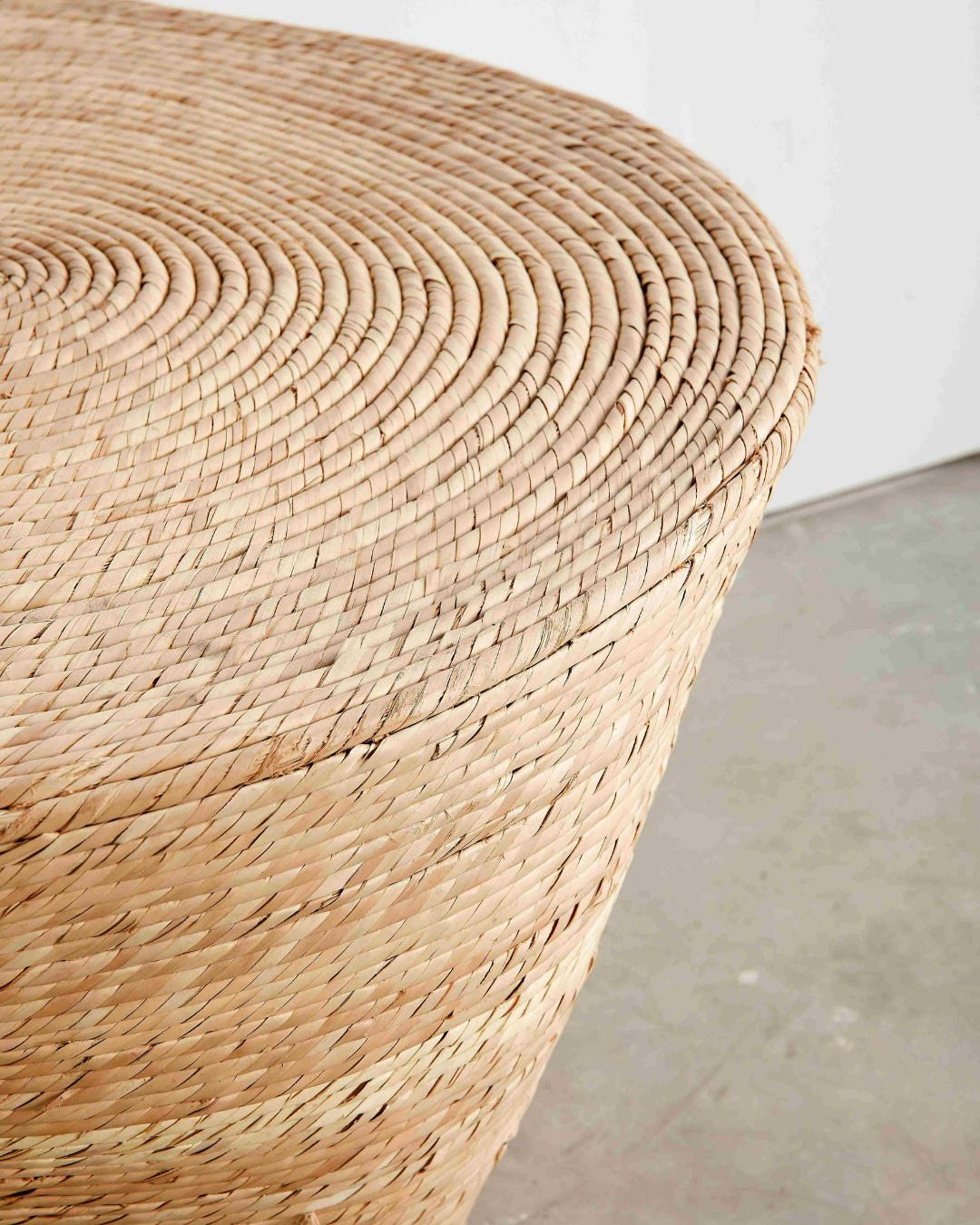 Close-up of a woven wicker stool with a neutral background