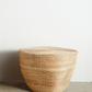 Woven straw stool against a plain white wall