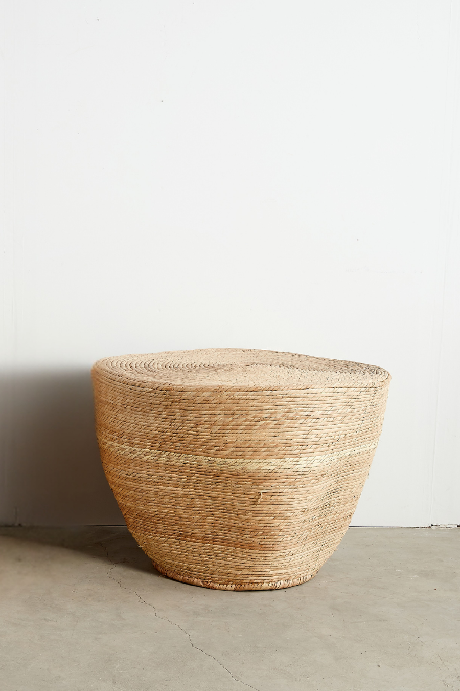 Woven straw stool against a plain white wall