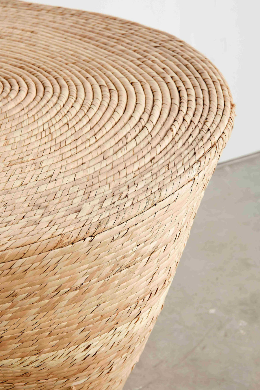 Close-up of a woven wicker stool with a neutral background