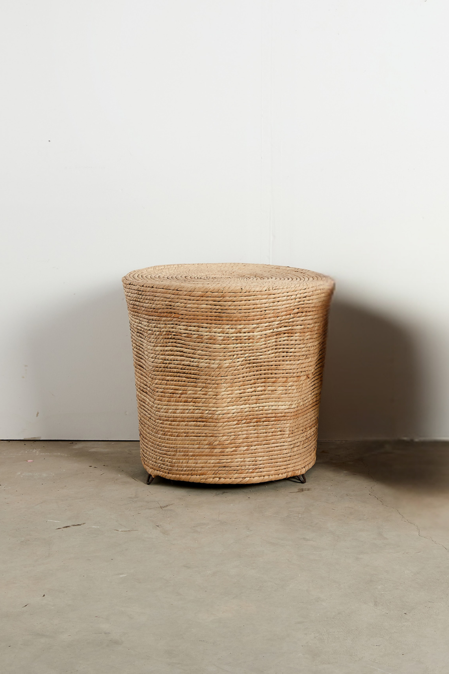 Woven basket on a concrete floor with a white wall background