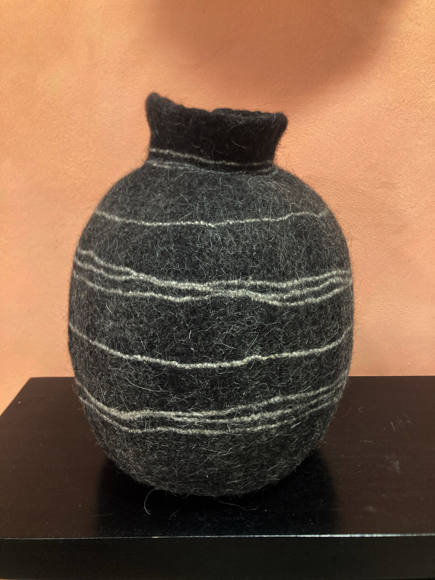 Textured black and gray spherical object on a brown surface