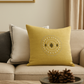 Yellow decorative pillow on a beige sofa with a bowl of pinecones and books on a coffee table.