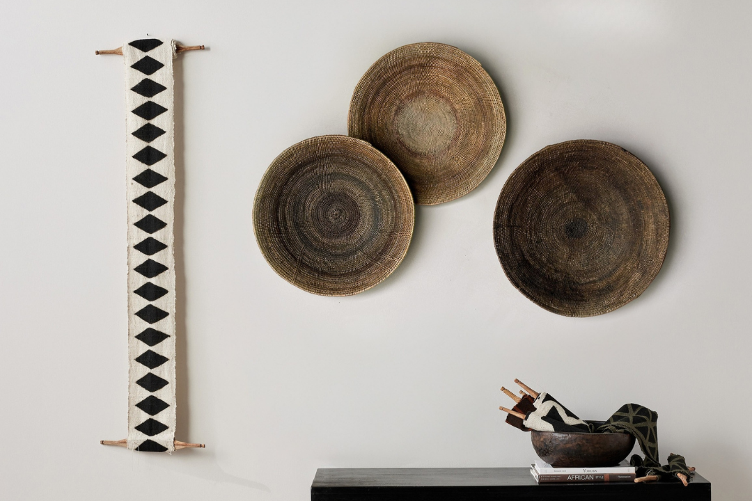 Decorative wall art with circular wooden pieces and a black console table against a white wall.