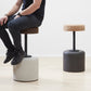 Designer Laurie Wiid van Heerden demonstrates the scale of Kanju's Wiid Swivel Cork and Concrete Barstool, offering a real-world perspective on its size and ergonomic design. This image captures Laurie seated on the innovative barstool, which combines the warmth of cork with the strength of concrete, showcasing the piece's functional elegance and sustainable approach to modern furniture design.