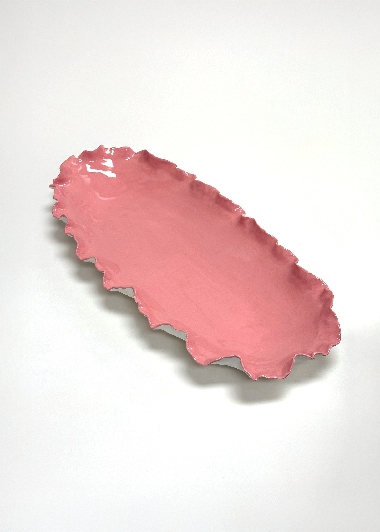 Pink ceramic dish with wavy edge on a white background
