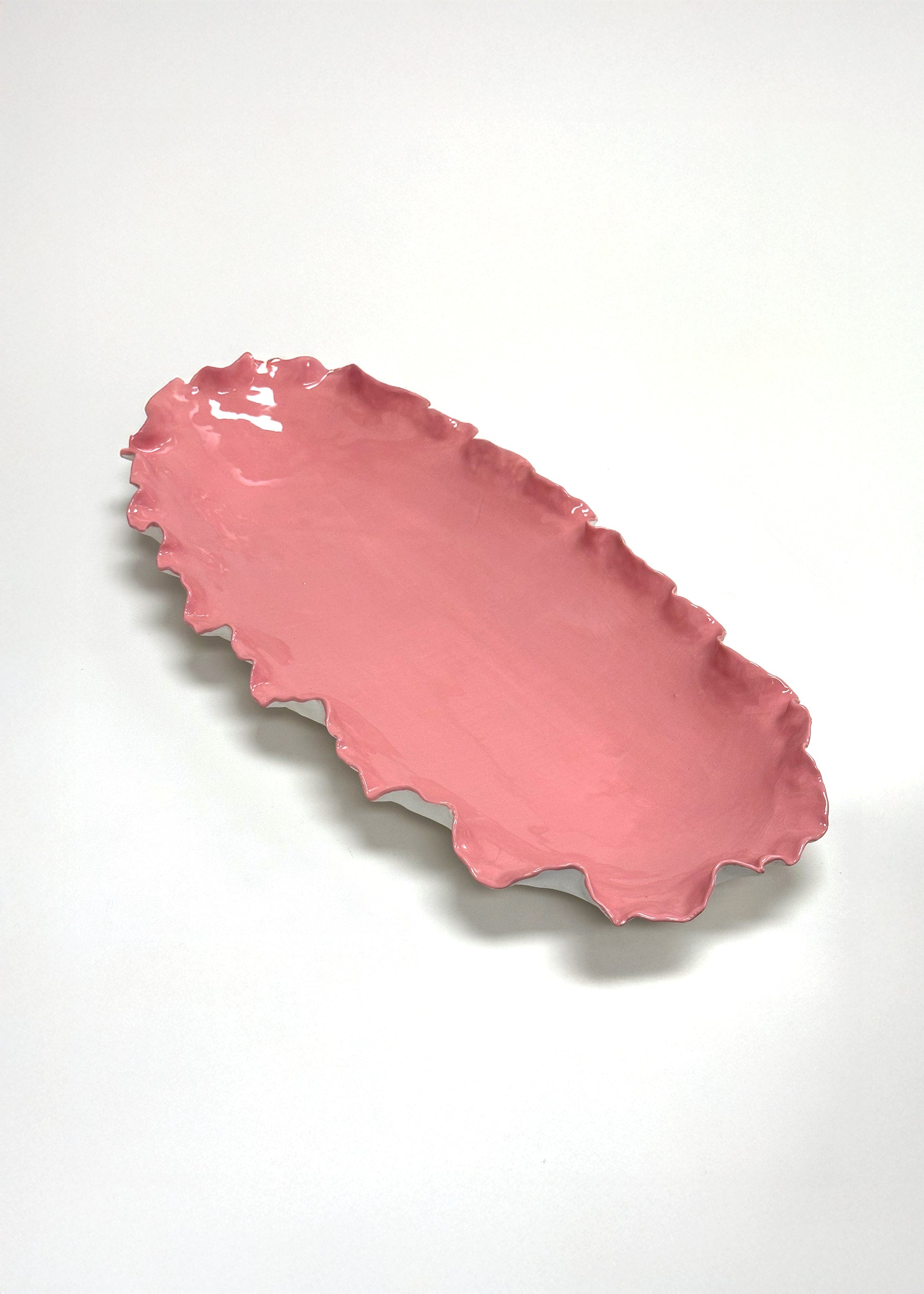 Pink ceramic dish with wavy edge on a white background