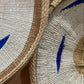 Close-up of woven mats with blue leaf patterns on a textured surface