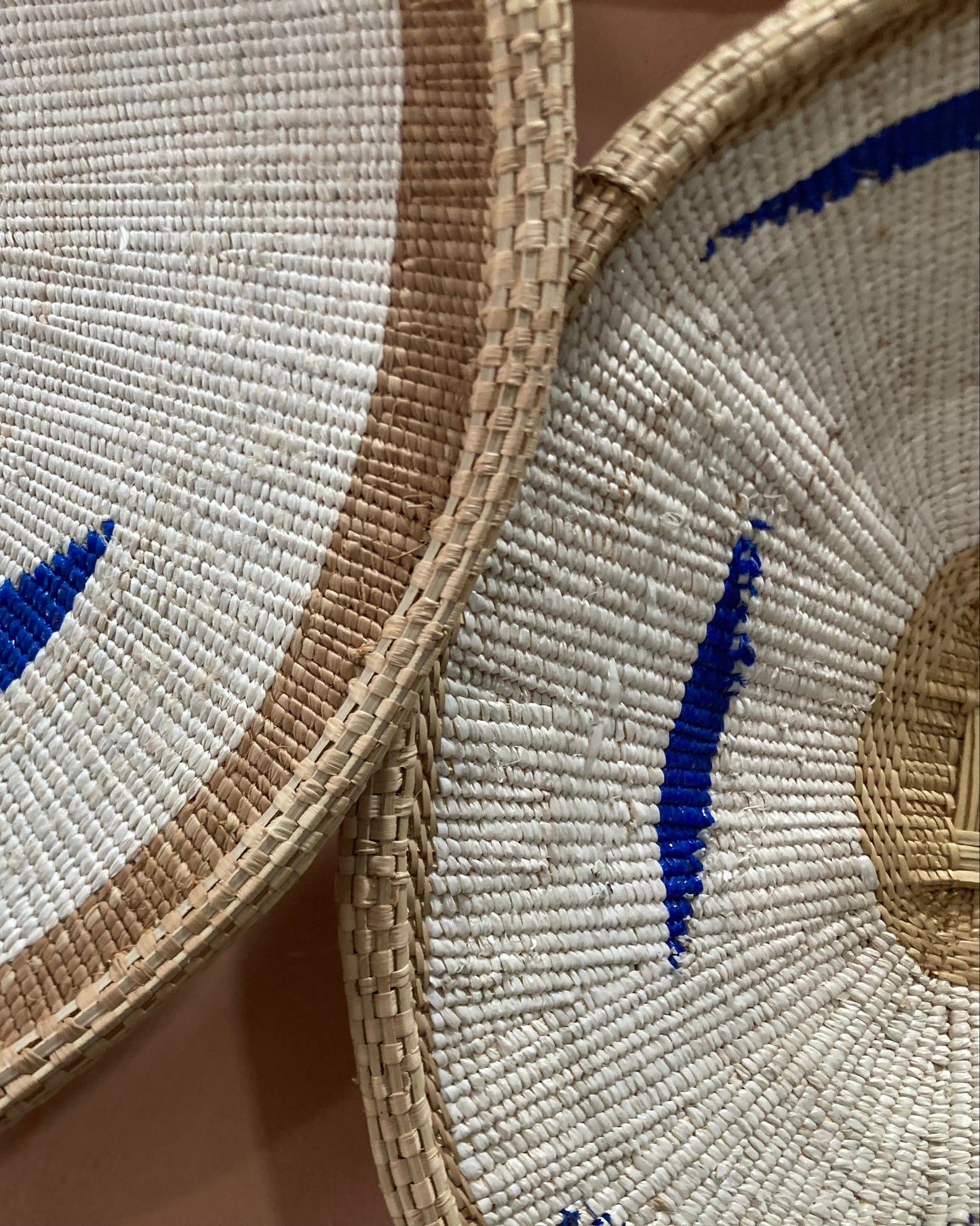 Close-up of woven mats with blue leaf patterns on a textured surface