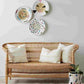 Wicker sofa with decorative pillows in a room with colorful plates on the wall.
