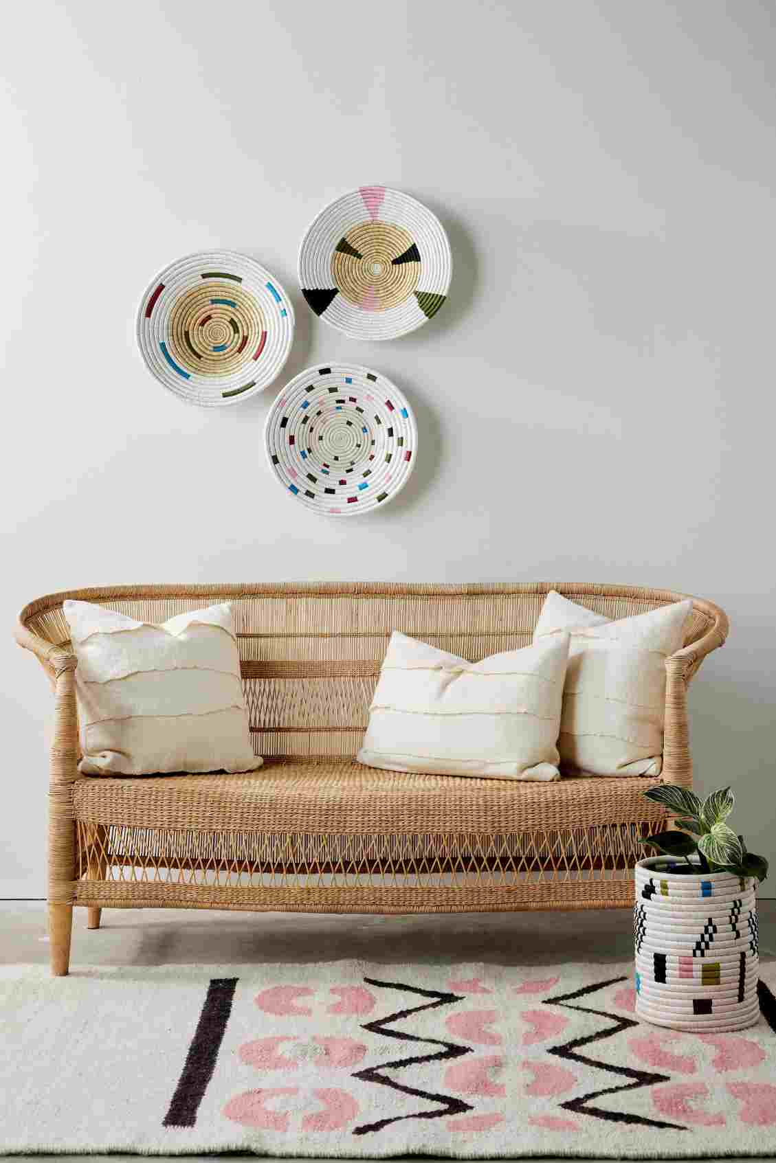 Wicker sofa with decorative pillows in a room with colorful plates on the wall.