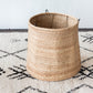 Woven basket on a patterned rug with a white wall background