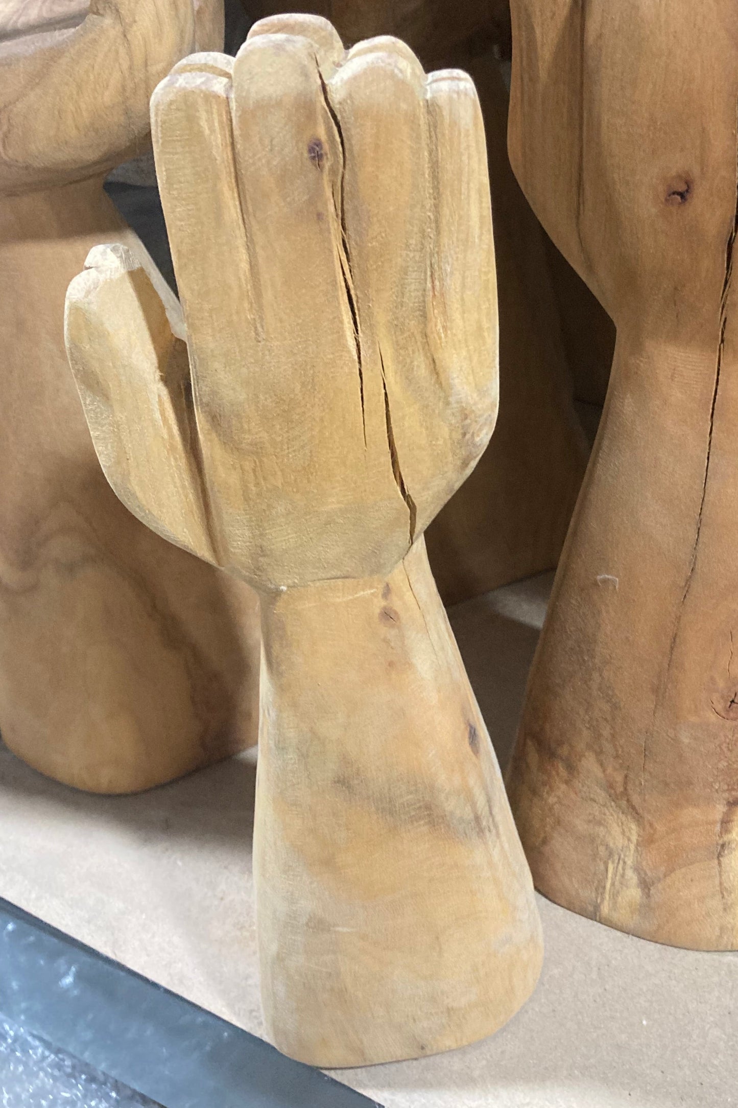 Wooden mannequin hands and arms stacked together on a surface.