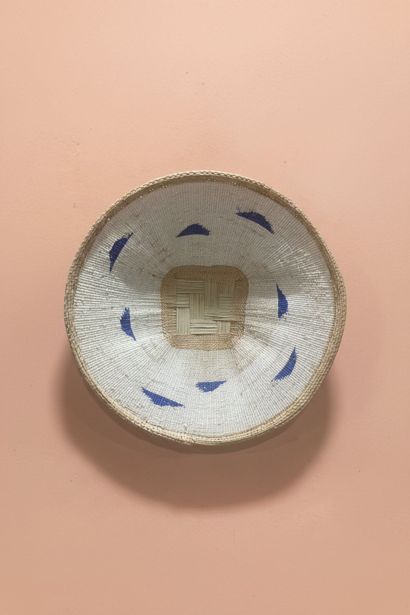 Woven basket with blue patterns on a pink background