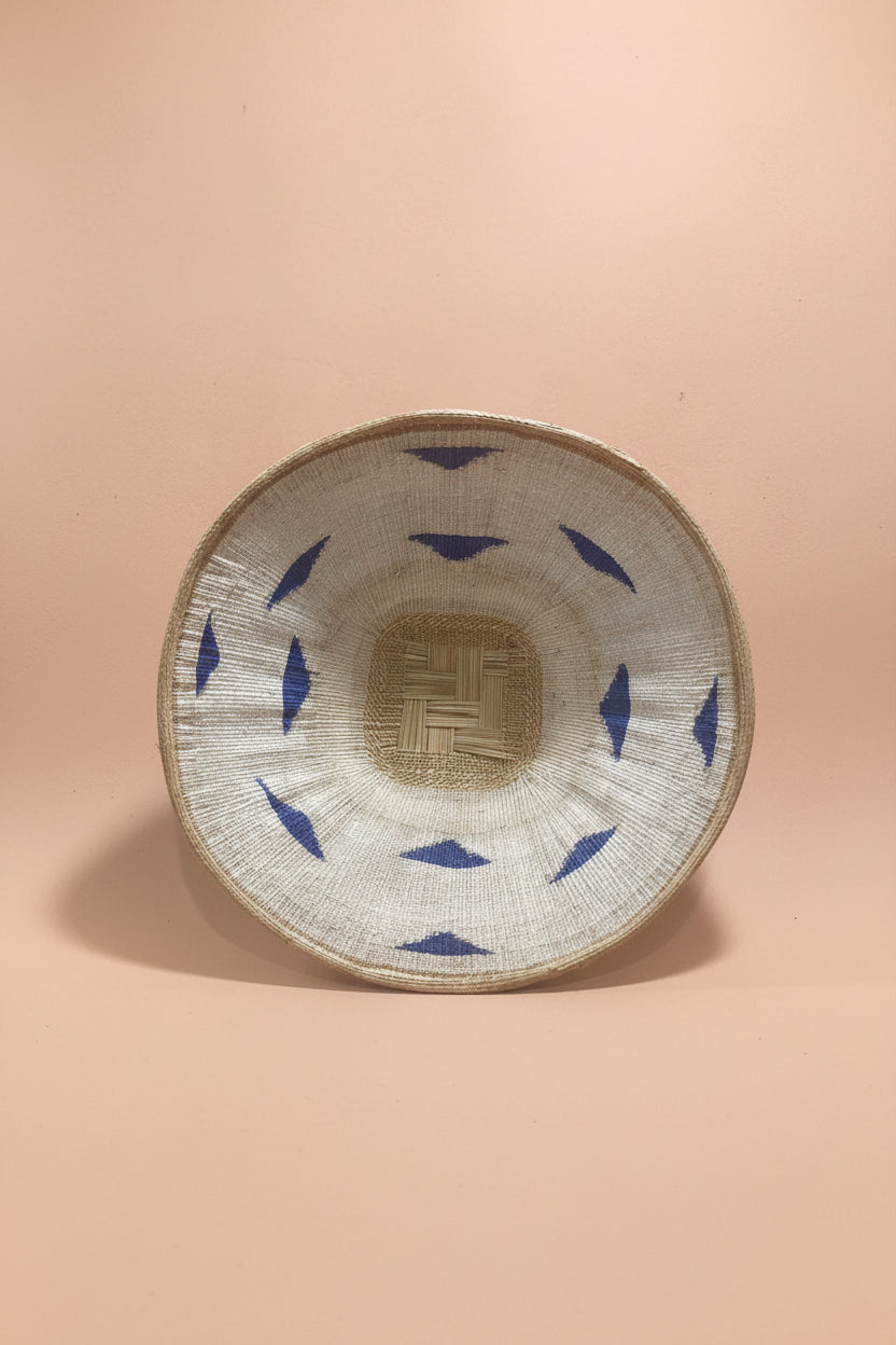 Woven basket with blue patterns on a pink background