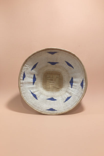 Woven basket with blue patterns on a pink background