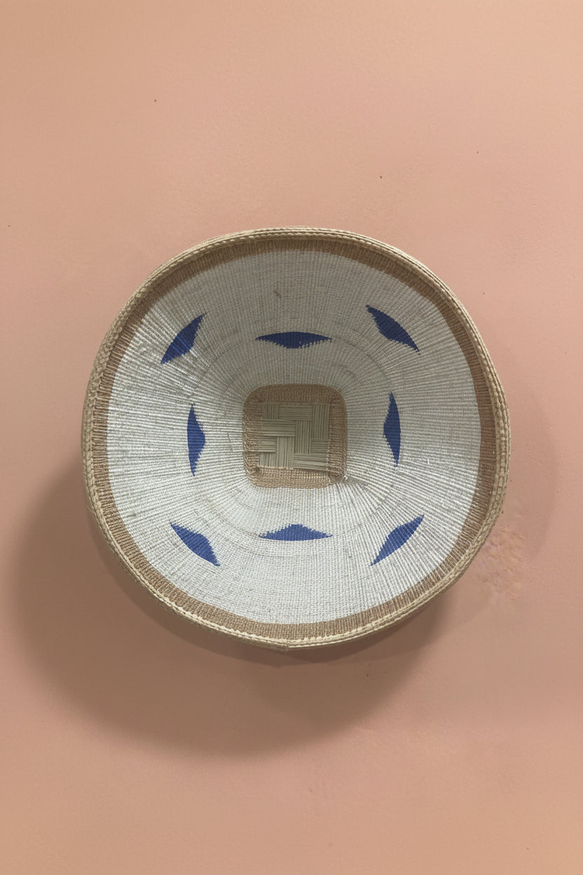Woven basket with blue patterns on a pink background