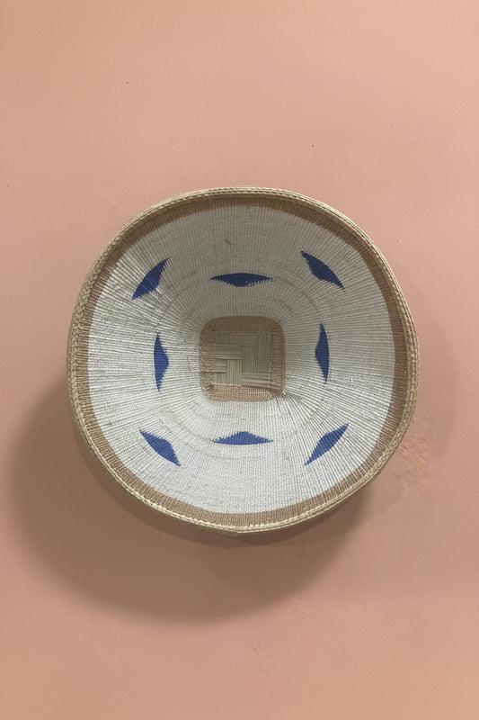 Woven basket with blue patterns on a pink background