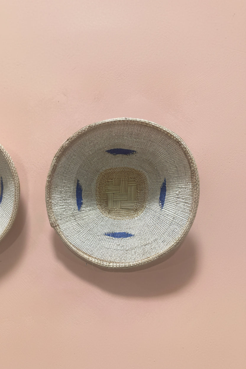 Woven basket with blue accents on a pink background