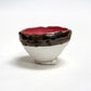 Ceramic bowl with a red interior and black and white exterior on a white background