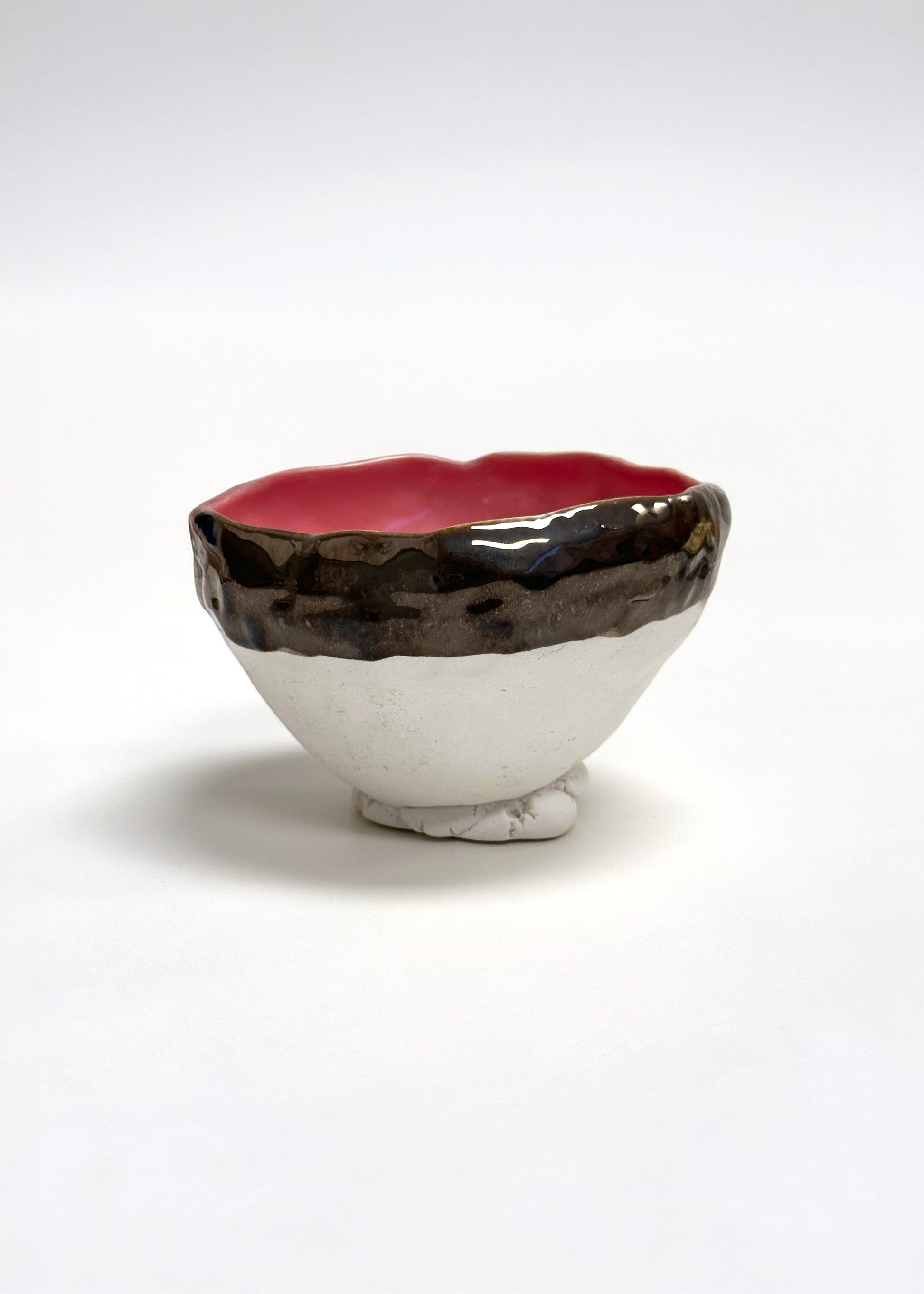 Ceramic bowl with a red interior and black and white exterior on a white background