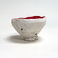 Ceramic bowl with a textured surface and red interior on a white background