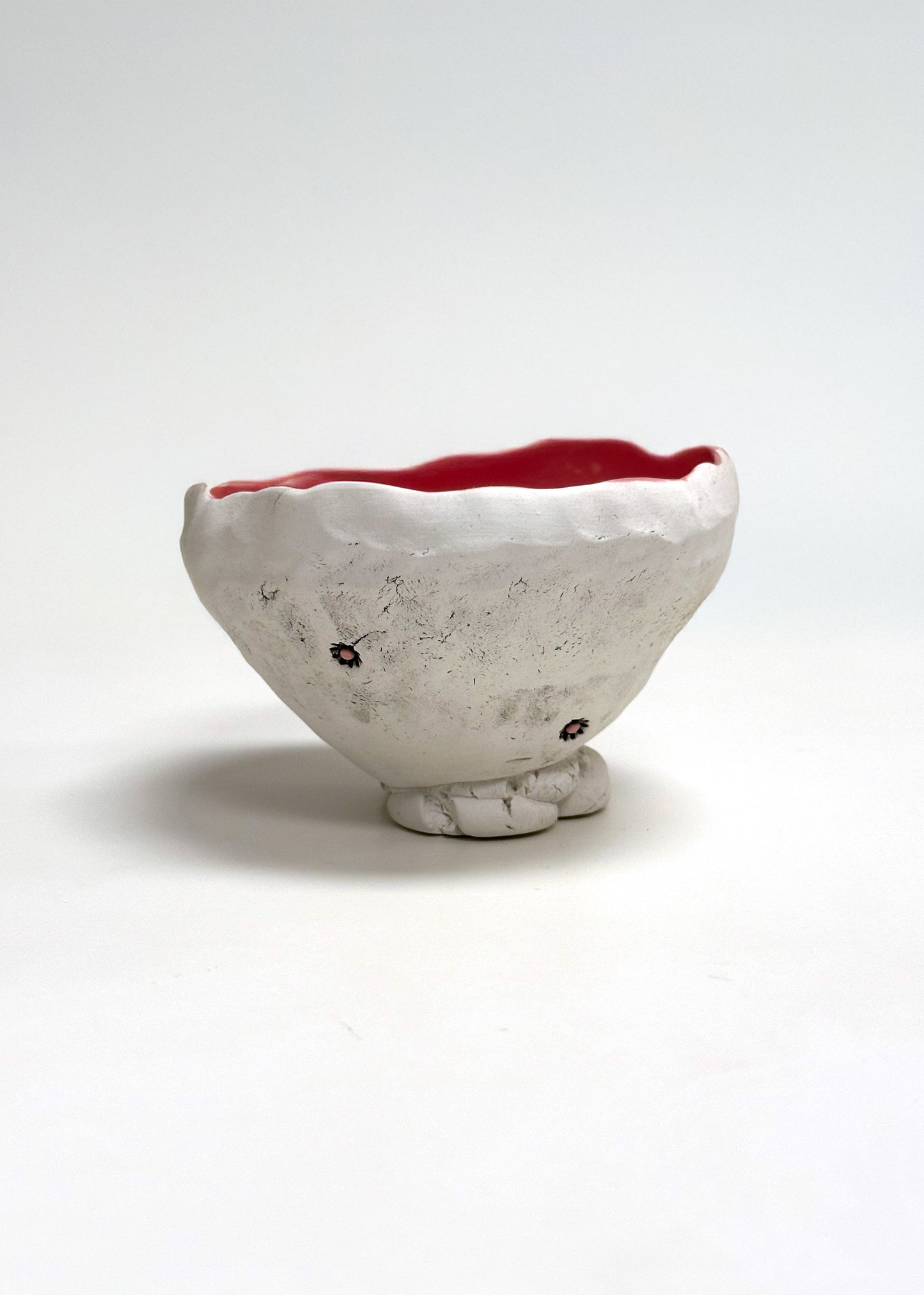 Ceramic bowl with a textured surface and red interior on a white background