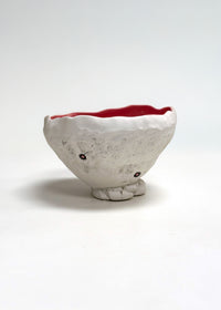 Ceramic bowl with a textured surface and red interior on a white background