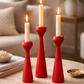 Three lit candles in red candle holders on a wooden table with a blurred background