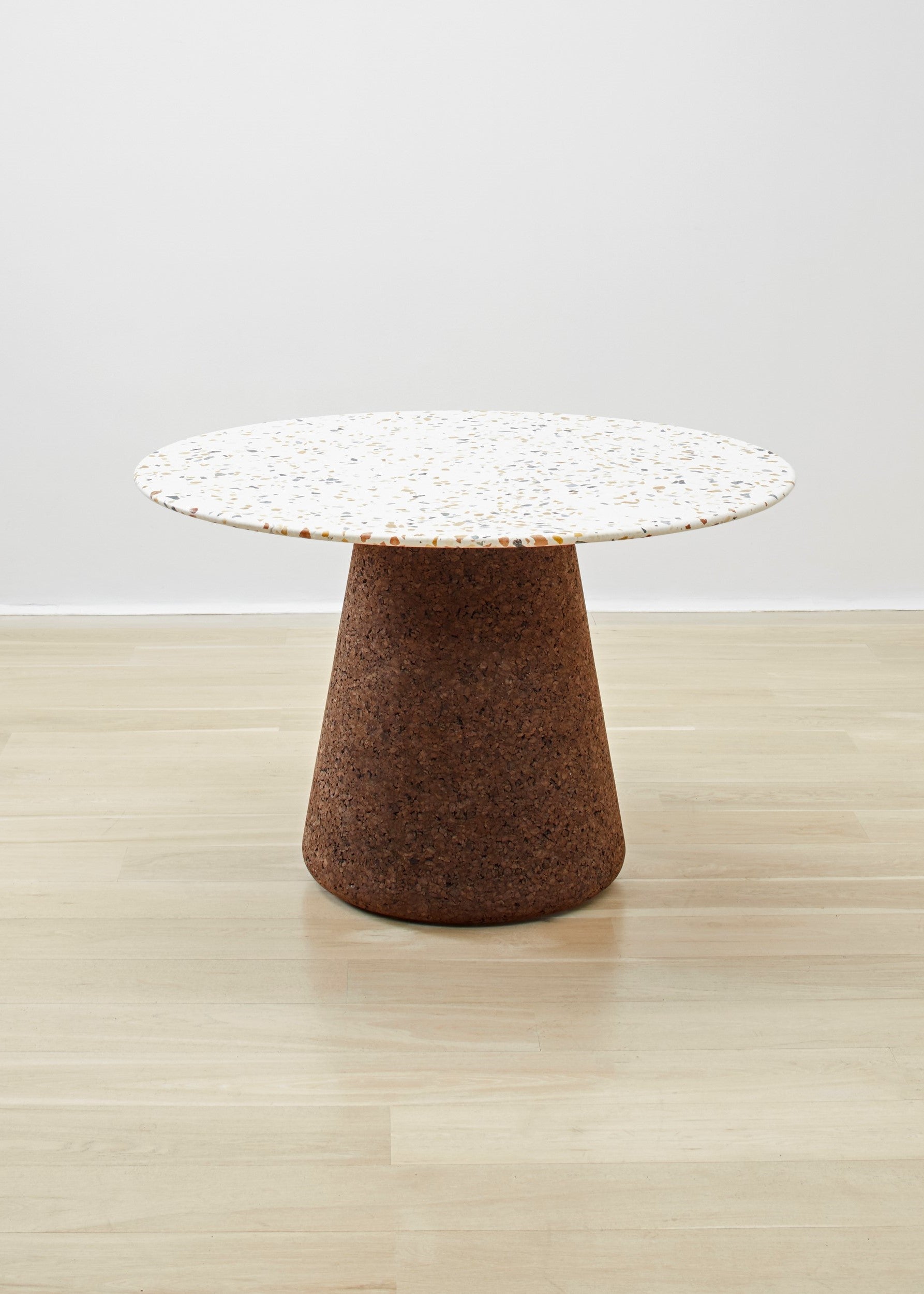 Elegant Kanju's Wiid Terrazzo and Cork Dining Table in Dark Cork, a masterpiece by Wiid Design, combines the raw beauty of terrazzo with the warmth of dark cork. This luxurious dining table not only stands as a testament to sustainable design but also to modern craftsmanship, making it a focal point in any sophisticated dining space.