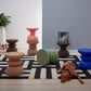 Colorful collection of Kanju Wiid Design African Cork Stools in vibrant hues of blue, pink, and green, alongside natural light and dark cork finishes. Each piece highlights sustainable luxury and artisanal craftsmanship, offering a unique seating solution that adds a burst of color and eco-friendly sophistication to any room.