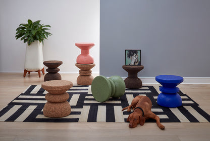 Colorful collection of Kanju Wiid Design African Cork Stools in vibrant hues of blue, pink, and green, alongside natural light and dark cork finishes. Each piece highlights sustainable luxury and artisanal craftsmanship, offering a unique seating solution that adds a burst of color and eco-friendly sophistication to any room.