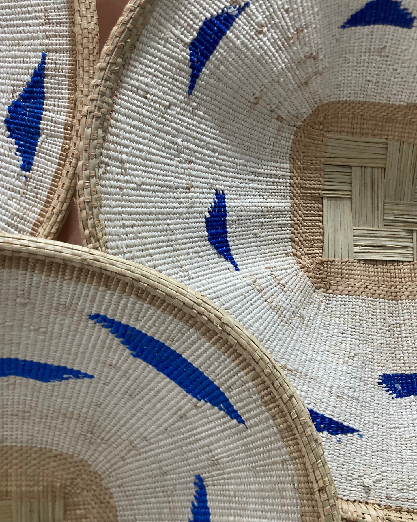 Three woven hats with blue decorative elements on a neutral background