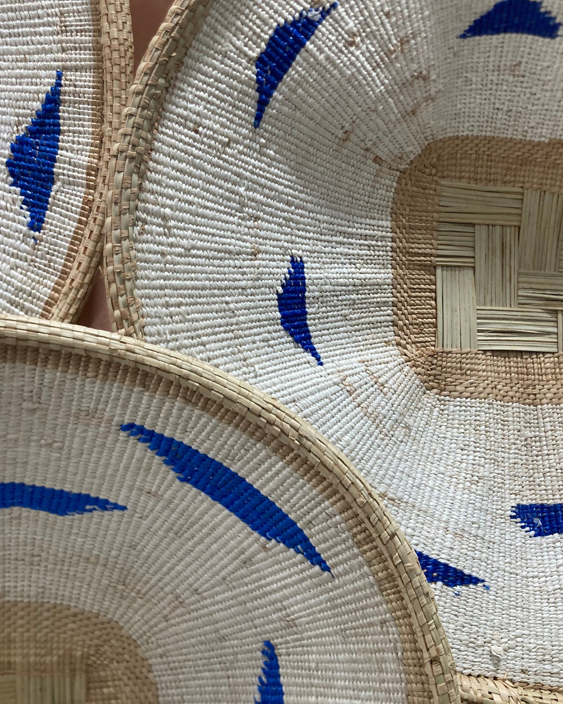 Three woven hats with blue decorative elements on a neutral background