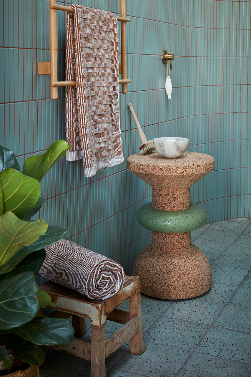 Chic bathroom setting featuring Kanju's Wiid Green Banded Tall African Cork Side Table with Ringed Design, perfectly complementing the space with its eco-friendly elegance. The image displays the table's unique ringed texture and vibrant green accent, adding a touch of sustainable luxury beside a freestanding bathtub, illustrating the versatility and modern aesthetic of cork in interior design