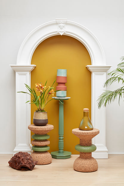 Artfully styled image featuring Kanju's Wiid Green Banded Tall African Cork Side Tables in both Stacked and Ringed designs. The photograph highlights the elegant interplay of natural cork texture with sophisticated green bands, set in a curated interior space that underscores their modern, sustainable beauty. These side tables exemplify luxury and eco-conscious design, perfectly blending with contemporary decor.