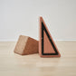 Close-up view of the bottom details of Kanju's Wiid Painted Triangle Cork Seat in a soft pink shade, highlighting the meticulous craftsmanship and unique design. The eco-friendly cork seat showcases innovative construction techniques, offering both style and sustainability in a contemporary home decor piece