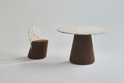 Elegant dining set from Kanju featuring the Wiid Design Terrazzo and Cork Dining Table in Dark Cork, paired with matching Wiid Design Terrazzo and Cork Dining Chairs. This sophisticated ensemble combines the unique beauty of terrazzo with the natural warmth of dark cork, offering a stunning example of sustainable luxury and innovative design. Ideal for those who appreciate artisan craftsmanship and eco-friendly materials in their dining space.