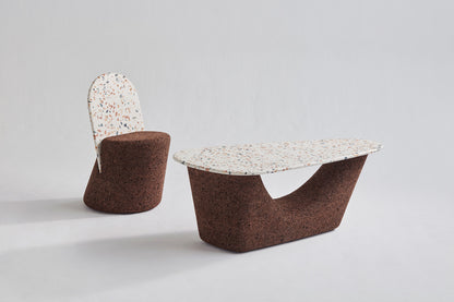 Kanju's sophisticated pairing: the Wiid Terrazzo and Cork Coffee/Side Table in Dark Cork next to the Wiid Terrazzo and Cork Dining Chair. This image captures the harmony between the two pieces, highlighting their luxurious terrazzo elements and dark cork accents. Designed by Wiid Design, the set exemplifies sustainable luxury, blending functionality with contemporary aesthetics for versatile use in modern living and dining spaces