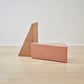 Kanju's collection featuring a Wiid Painted Triangle Cork Seat in a delicate pink hue next to its counterpart in natural light cork. This pairing showcases the versatility of the triangle cork seats, highlighting both the vibrant painted finish and the subtle elegance of the light cork. Perfect for adding a modern, eco-friendly touch to any interior space.