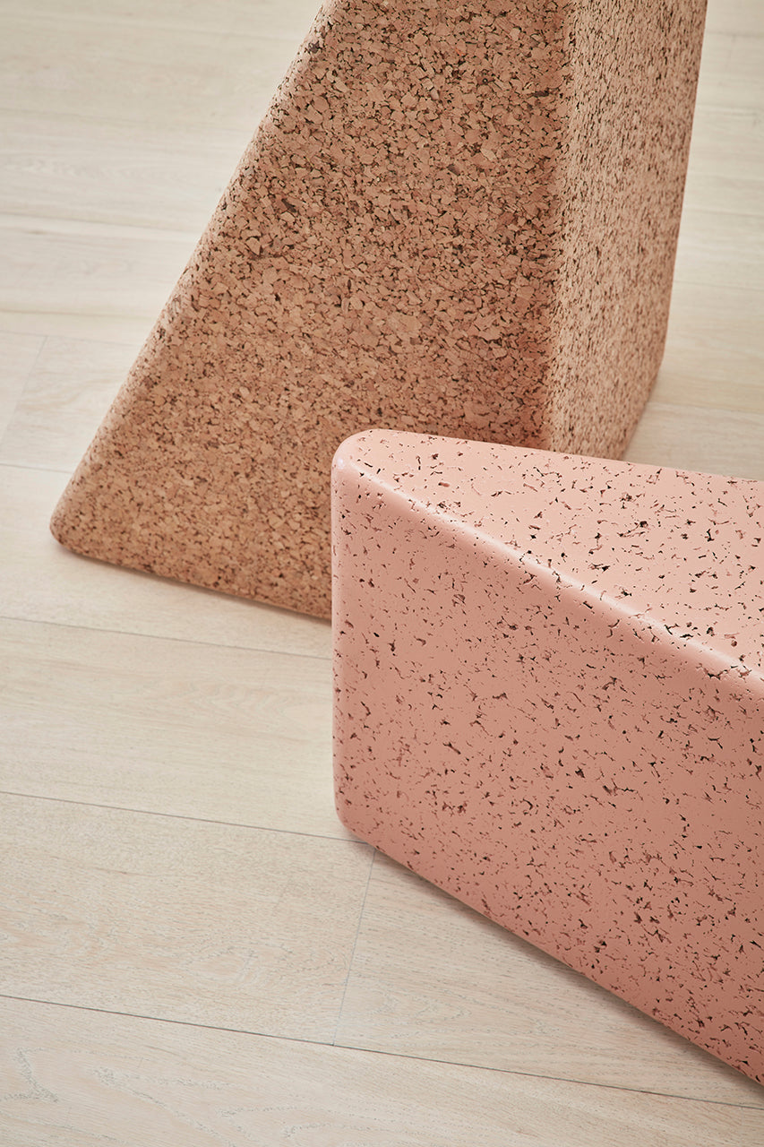 Close-up view of Kanju's Wiid Triangle Cork Seat/Side Table, showcasing the exquisite detail in light cork with a pink accent. This image highlights the texture and color contrast, emphasizing the piece's dual functionality and sustainable design. Ideal for adding a touch of sophistication and playful charm to any modern living space.